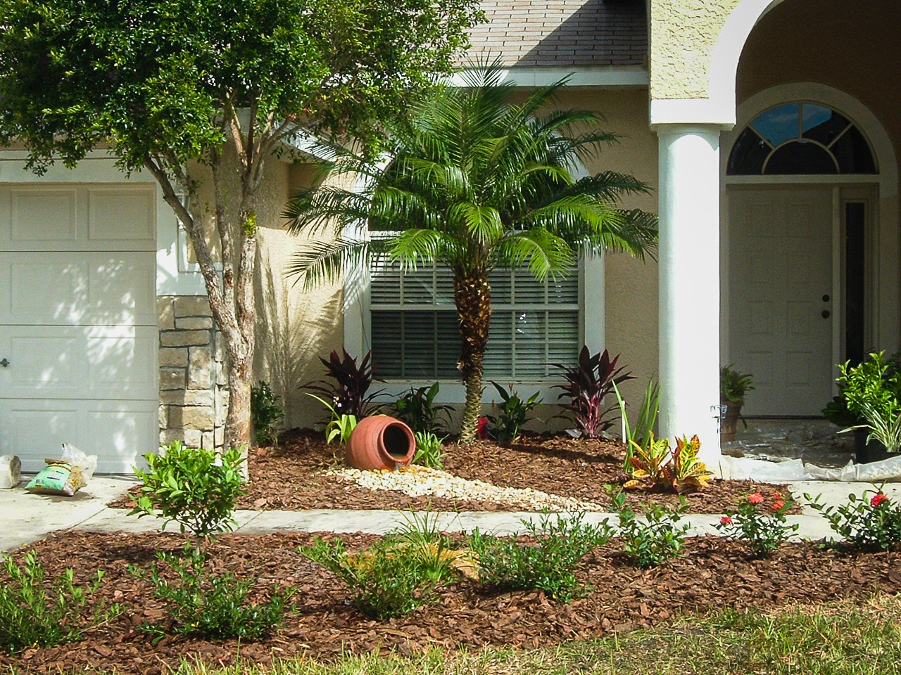 front yard landscaping with water fountain feature, garden bed with flowers and stone walkway to front door