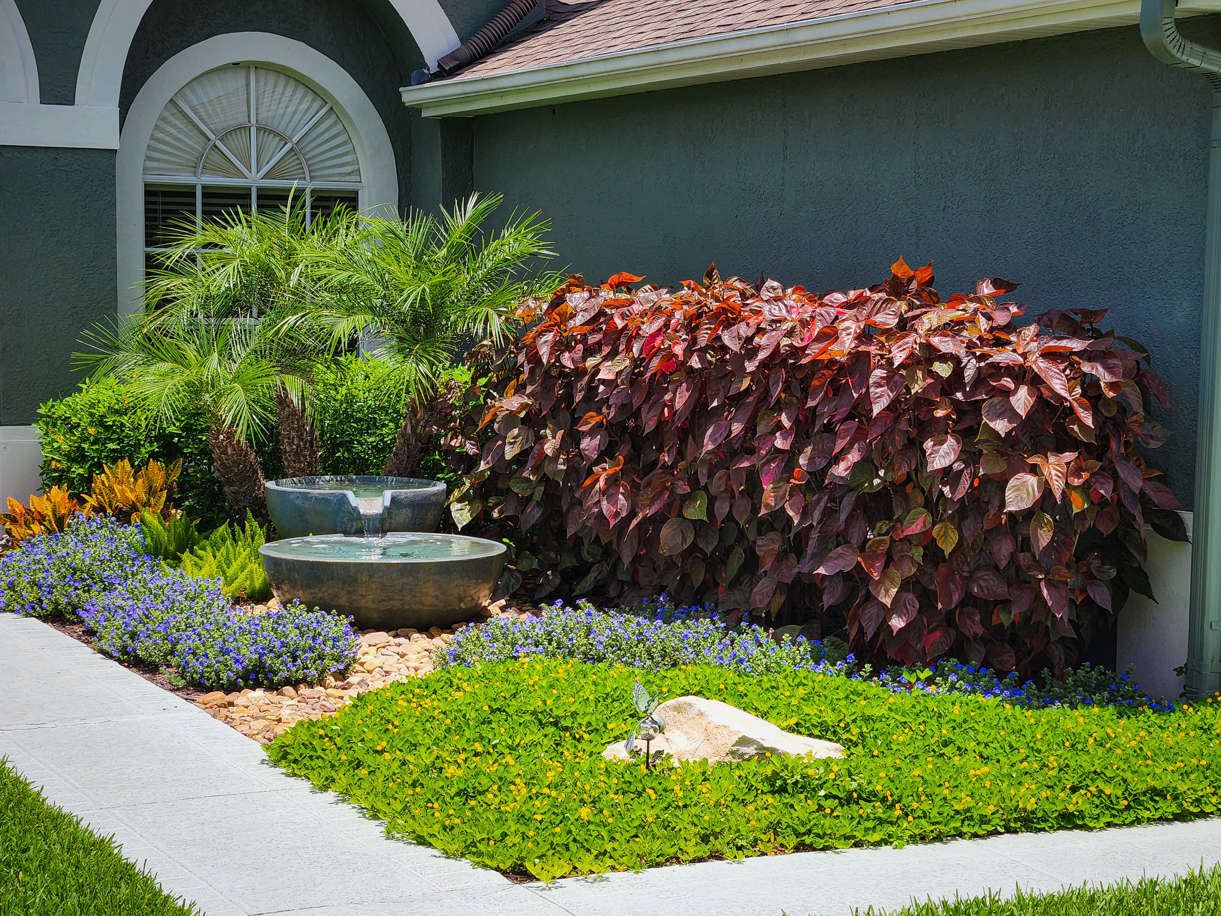 landscaping with water fountain, stone walkway and colorful plant garden